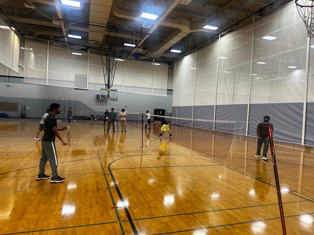 Players rally on badminton courts set up across the gym floor.