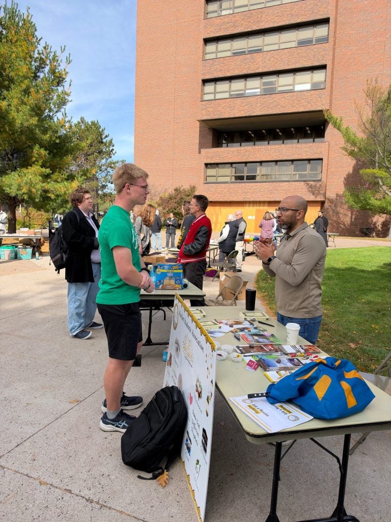 A man at the MSA table talks with a visitor over pamphlets, Quran translations and dates in paper cups.